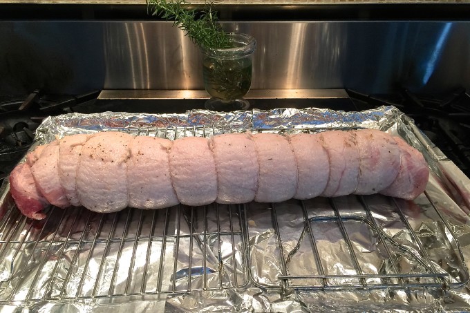 Pork Belly Porchetta is ready for baking. Tied with butcher's twine and ready for roasting, this Pork Belly Porchetta recipe is bold on flavor.