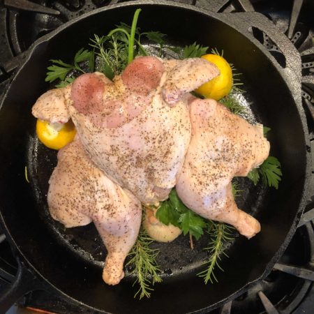 Place the chicken on top of the aromatics, herbs, and lemons.